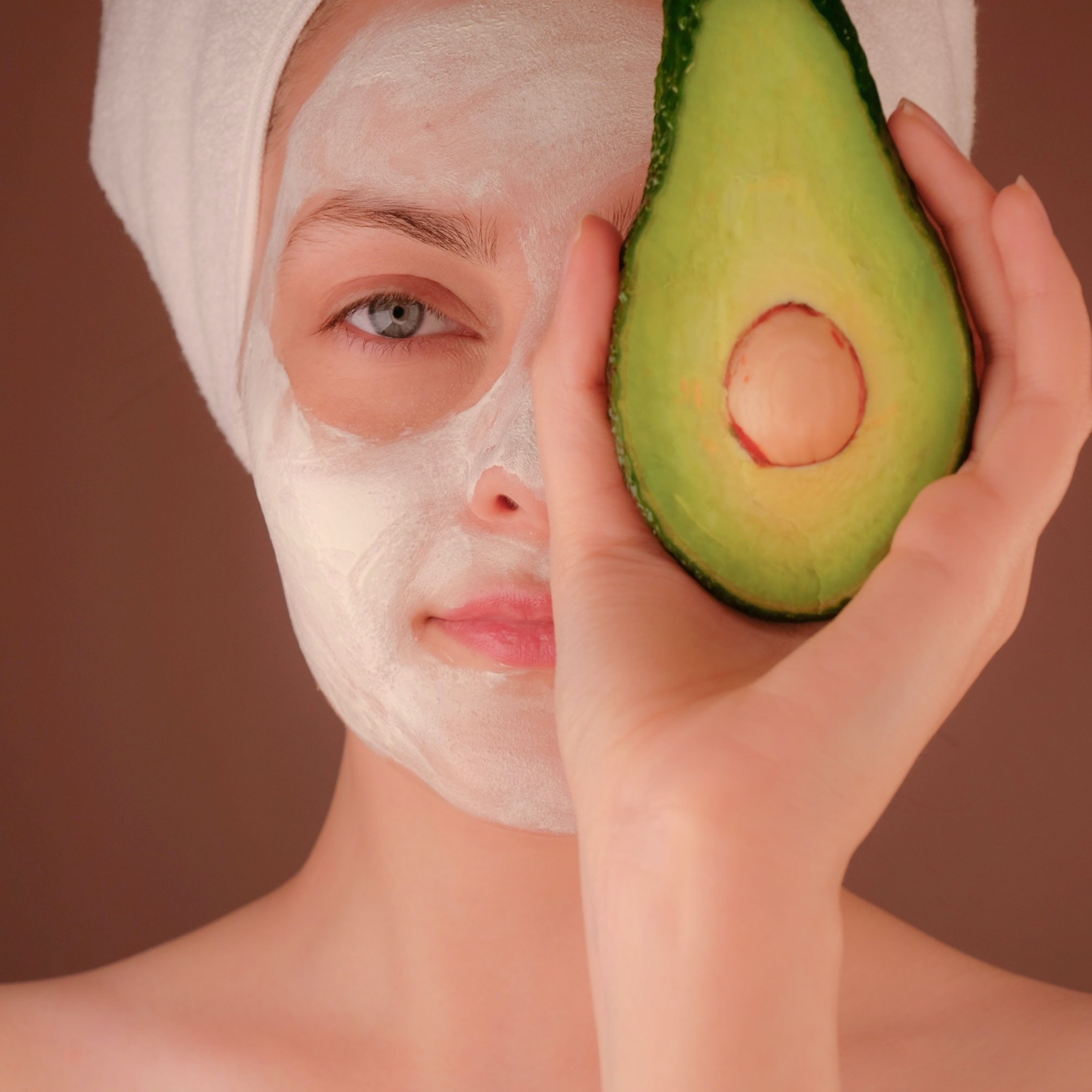 woman with a facial holding an avocado