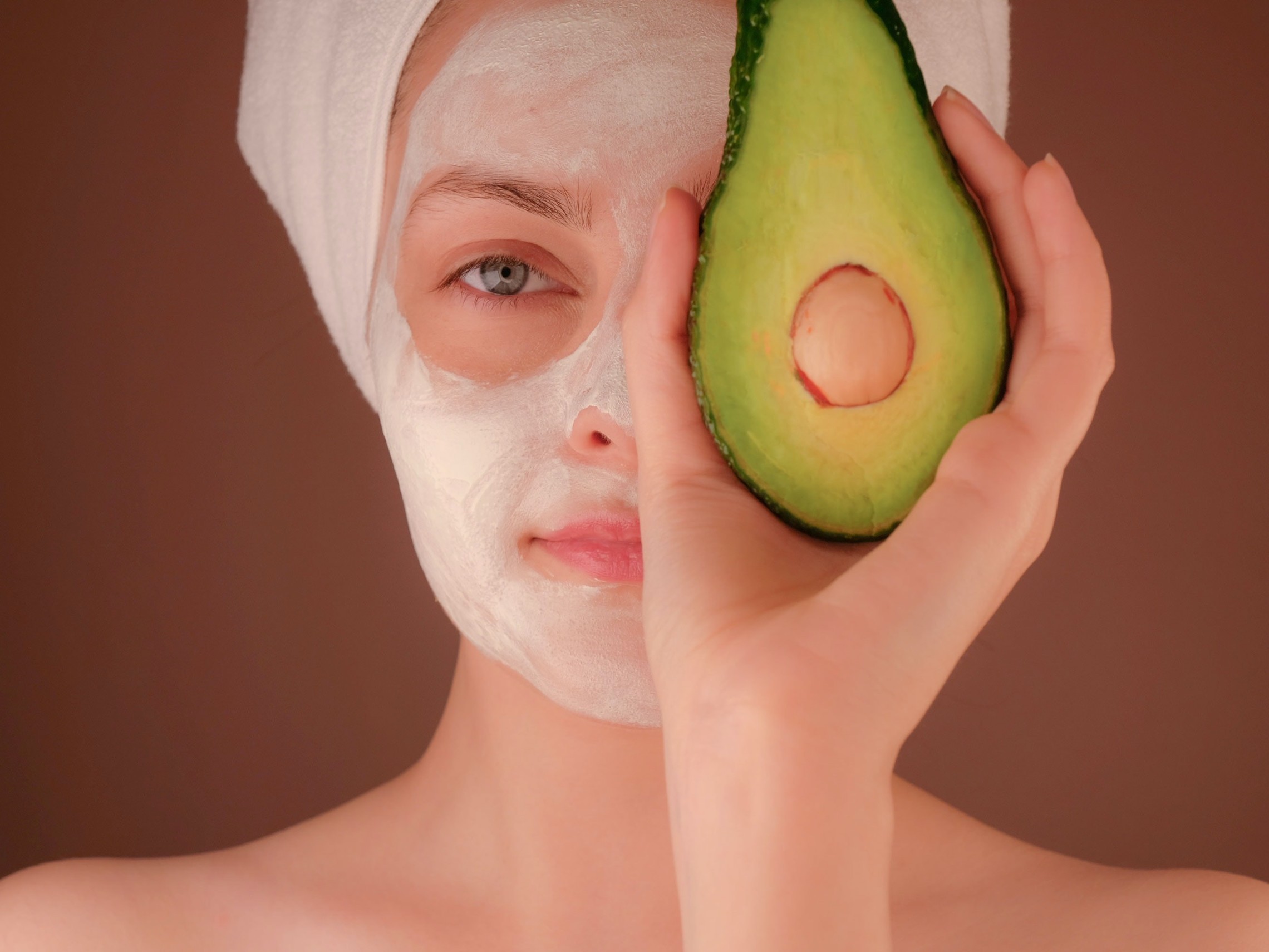 woman with a facial holding an avocado